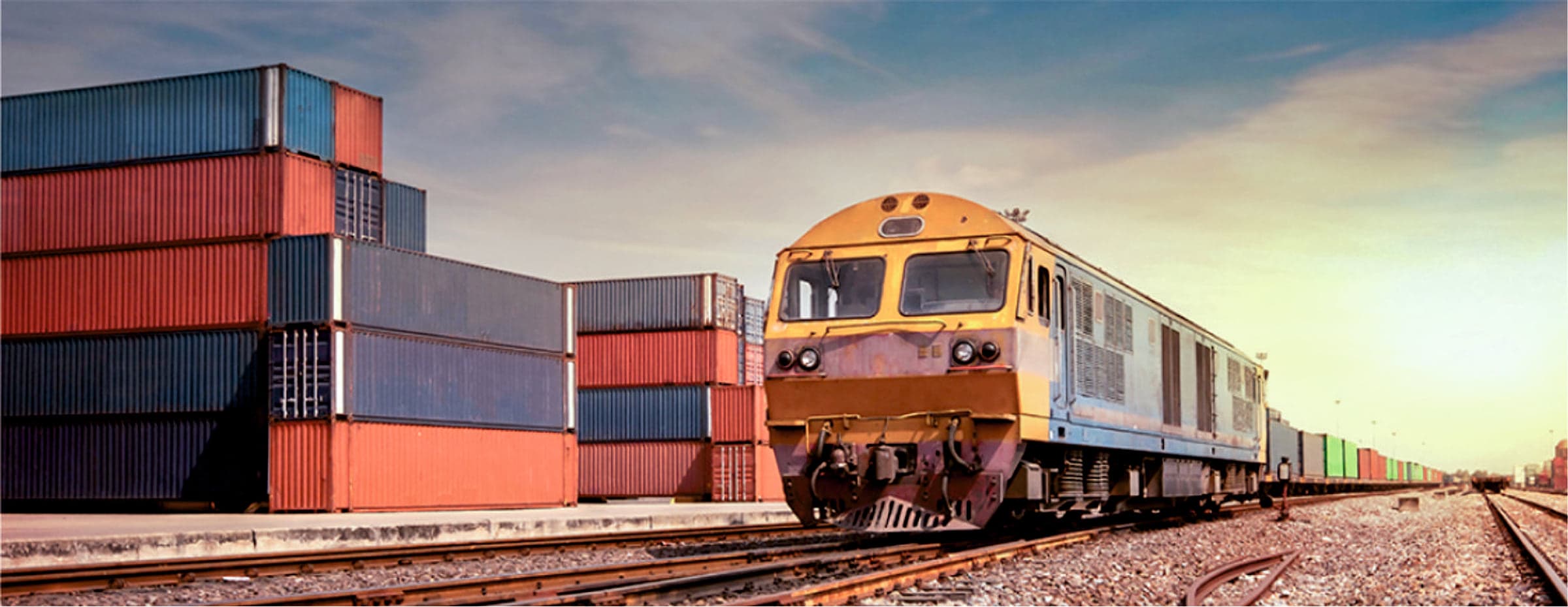 Freight train passing stacked containers