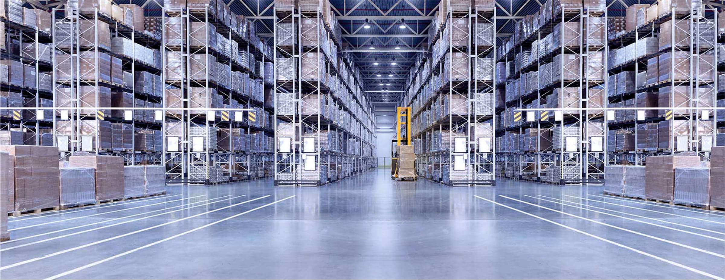 High-bay warehouse aisles with a forklift at work