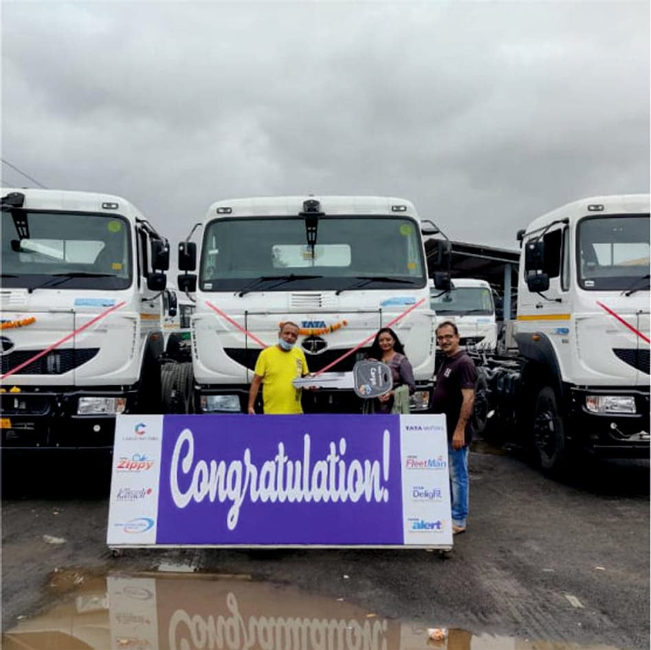 Team receiving keys in front of new trucks with a congratulations banner